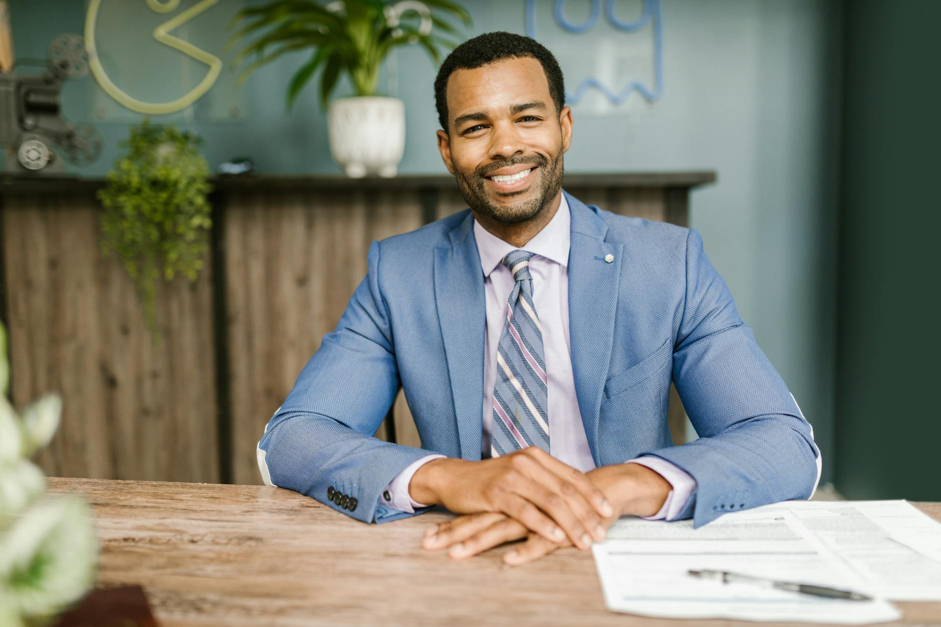 smiling man in blue suit sitting by the table