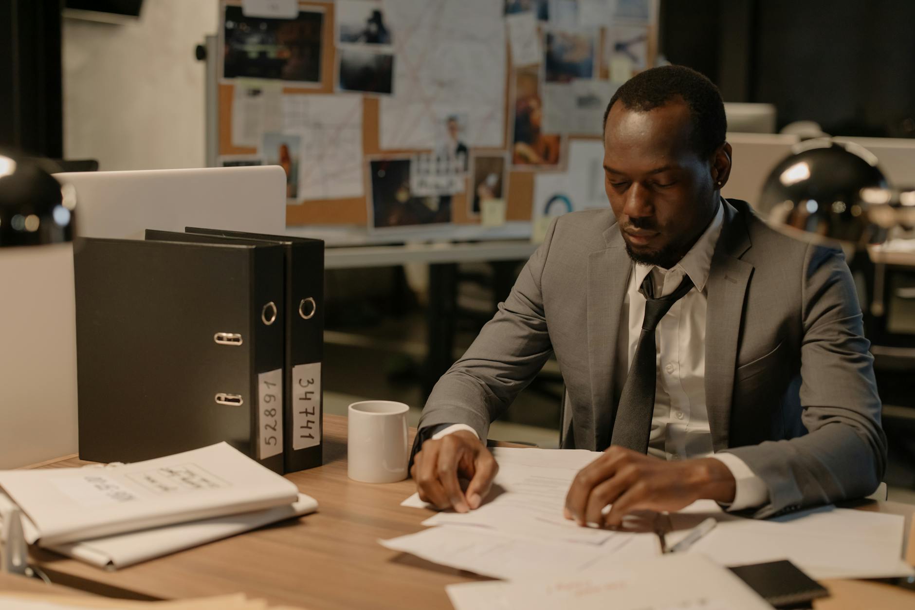 man in gray suit jacket looking at white paper