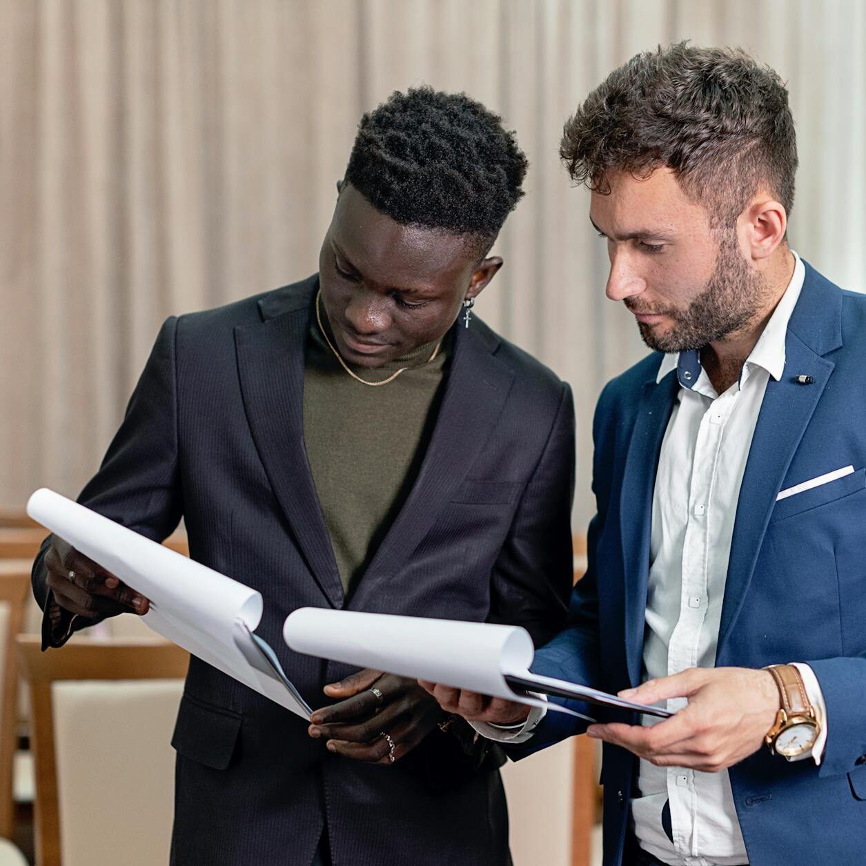 businessmen in black and blue suit having conversation while holding documents