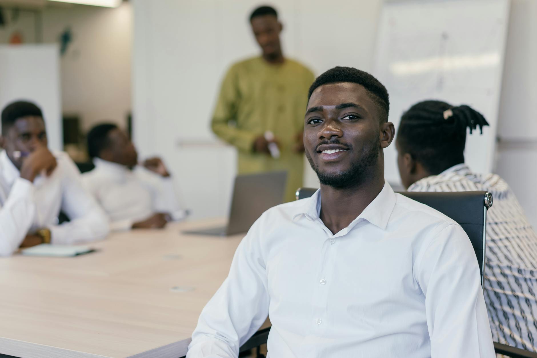 a man sitting on a chair inside a conference room smiling at the camera